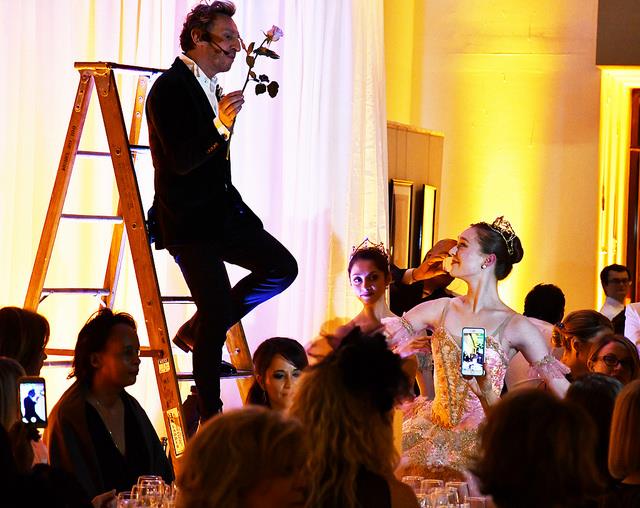 MAn holding a rose, stepping down of a ladder toward a ballerina; amidst a crowd. Photo Credit: French Embassy in the U.S.